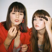 The duo Disgusting Sisters, one applying lipgloss & one applying eyeshadow